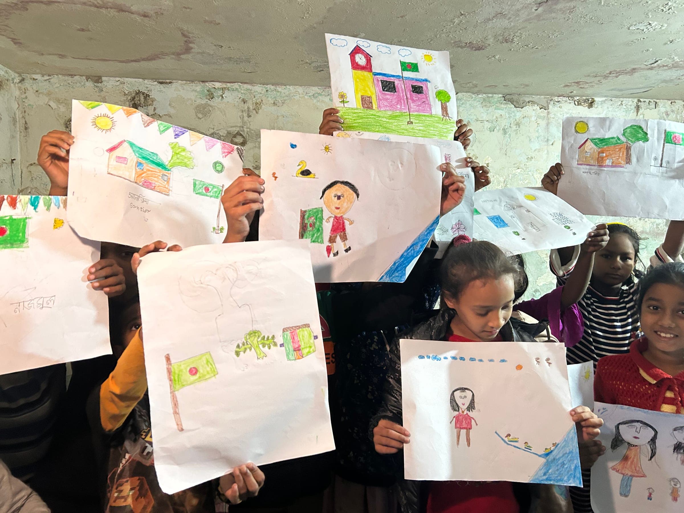 Children holding up their crayon drawings of houses and figures